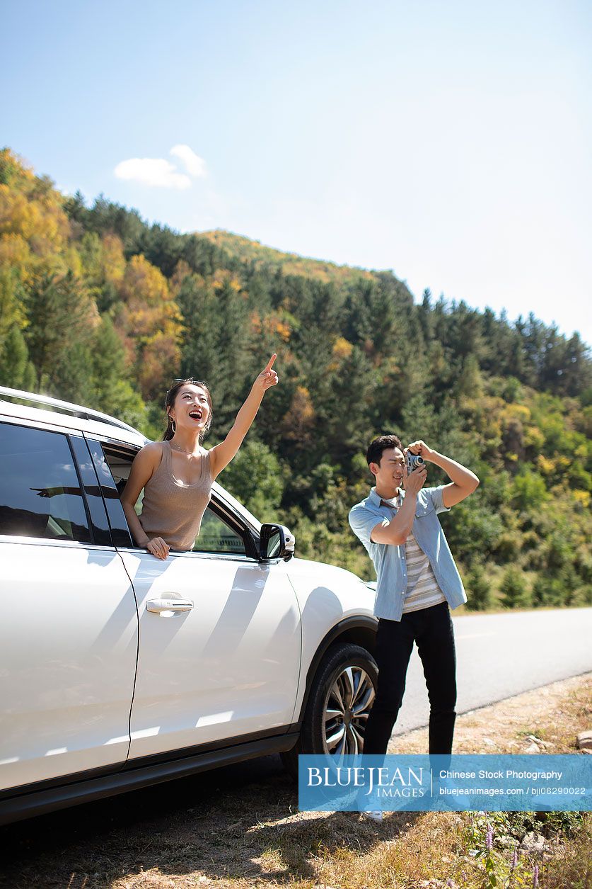 Happy young Chinese couple enjoying road trip