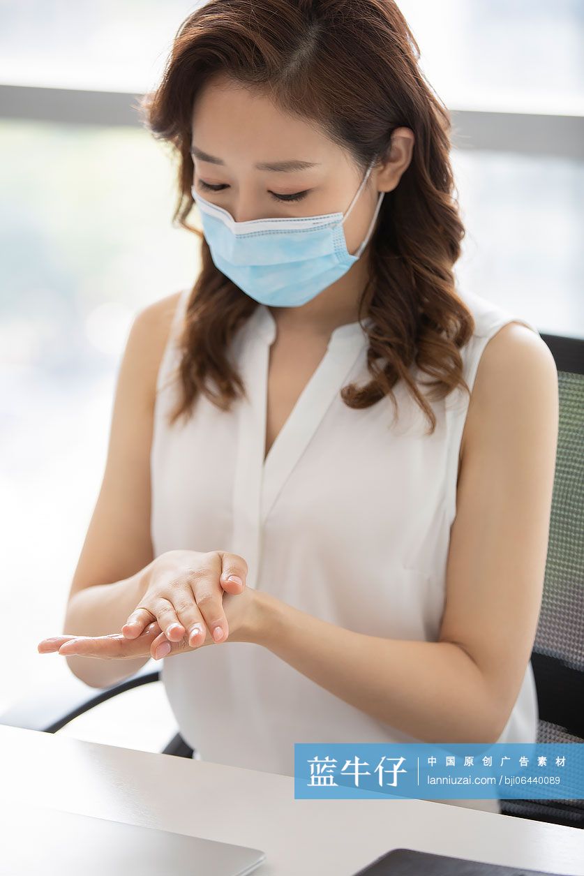 年轻的商务女士在办公室使用免洗洗手液