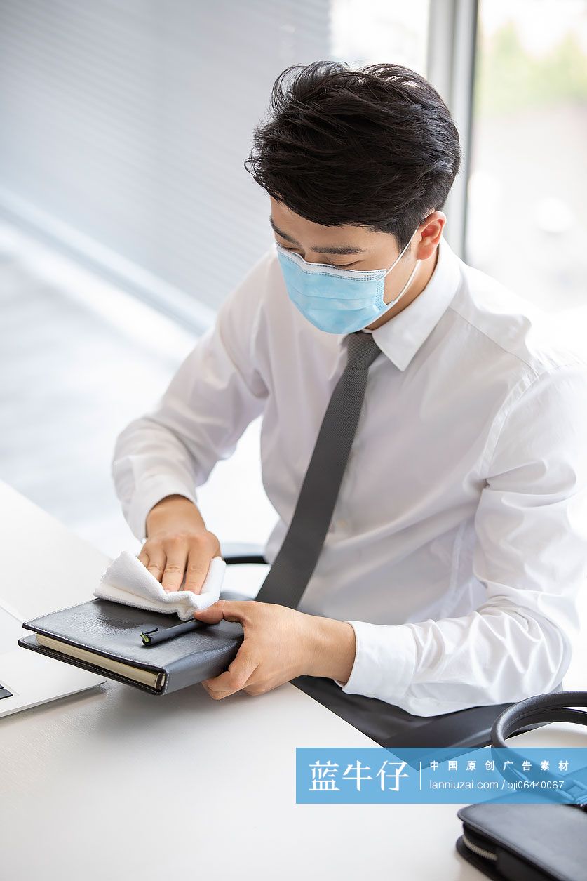 年轻的商务男士在办公室使用消毒液杀菌消毒