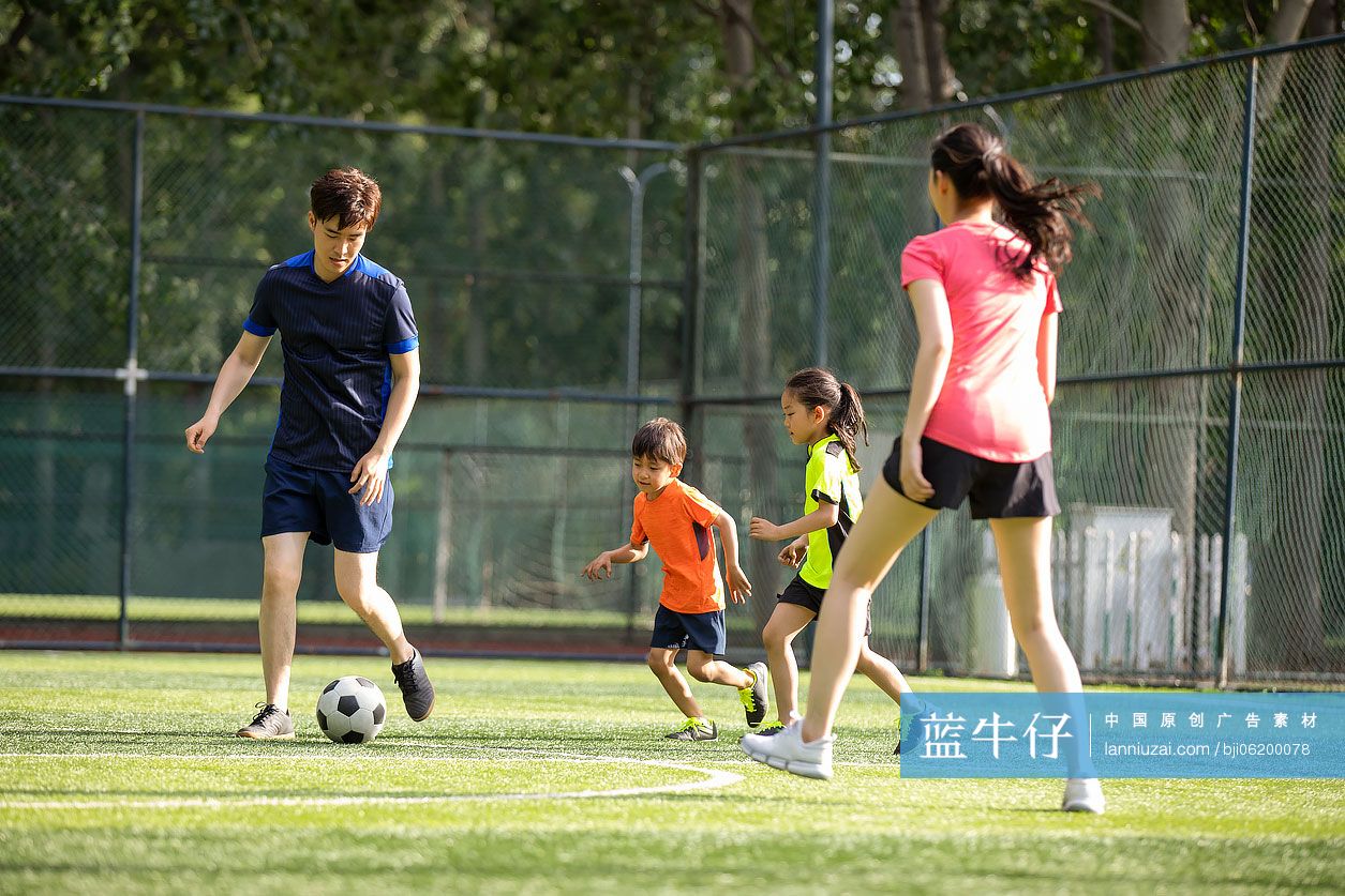 快乐的年轻家庭在足球场踢足球