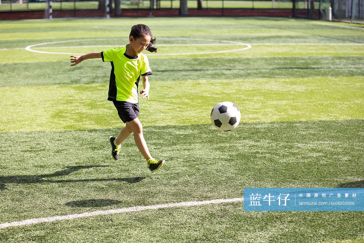 小女孩在足球场踢足球