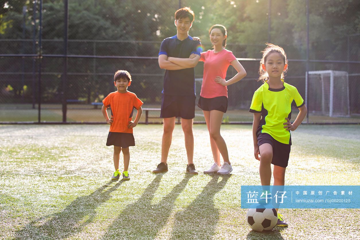 快乐的年轻家庭在足球场踢足球