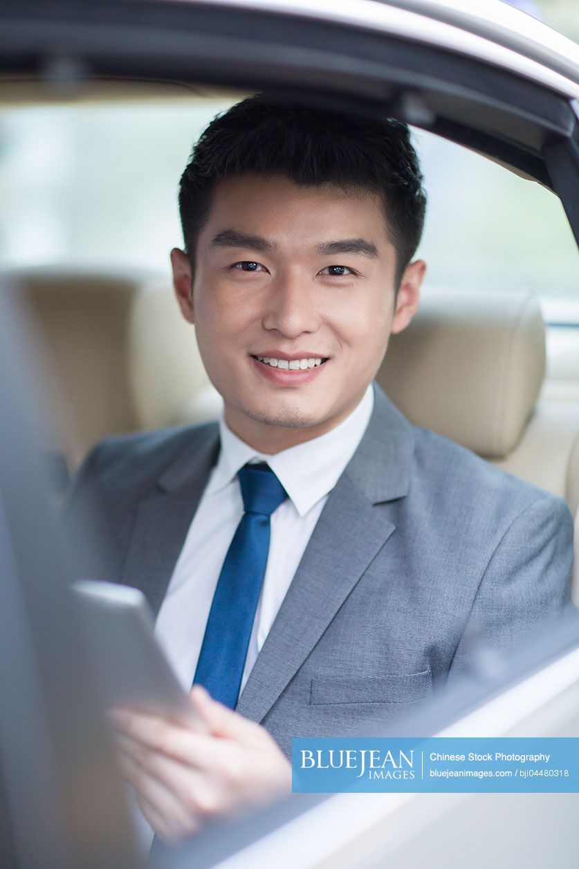 Chinese businessman sitting in car back seat