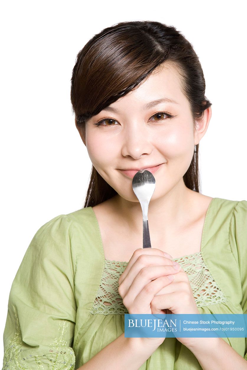 Portrait of young Chinese woman eating from spoon