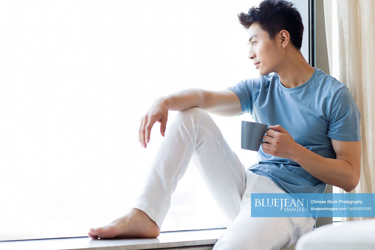 Young Chinese man drinking coffee at home