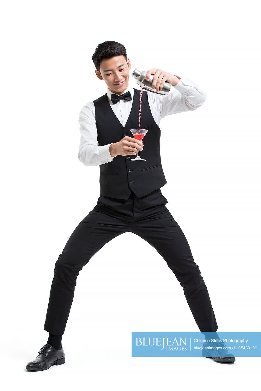 Cheerful young Chinese bartender pouring drink