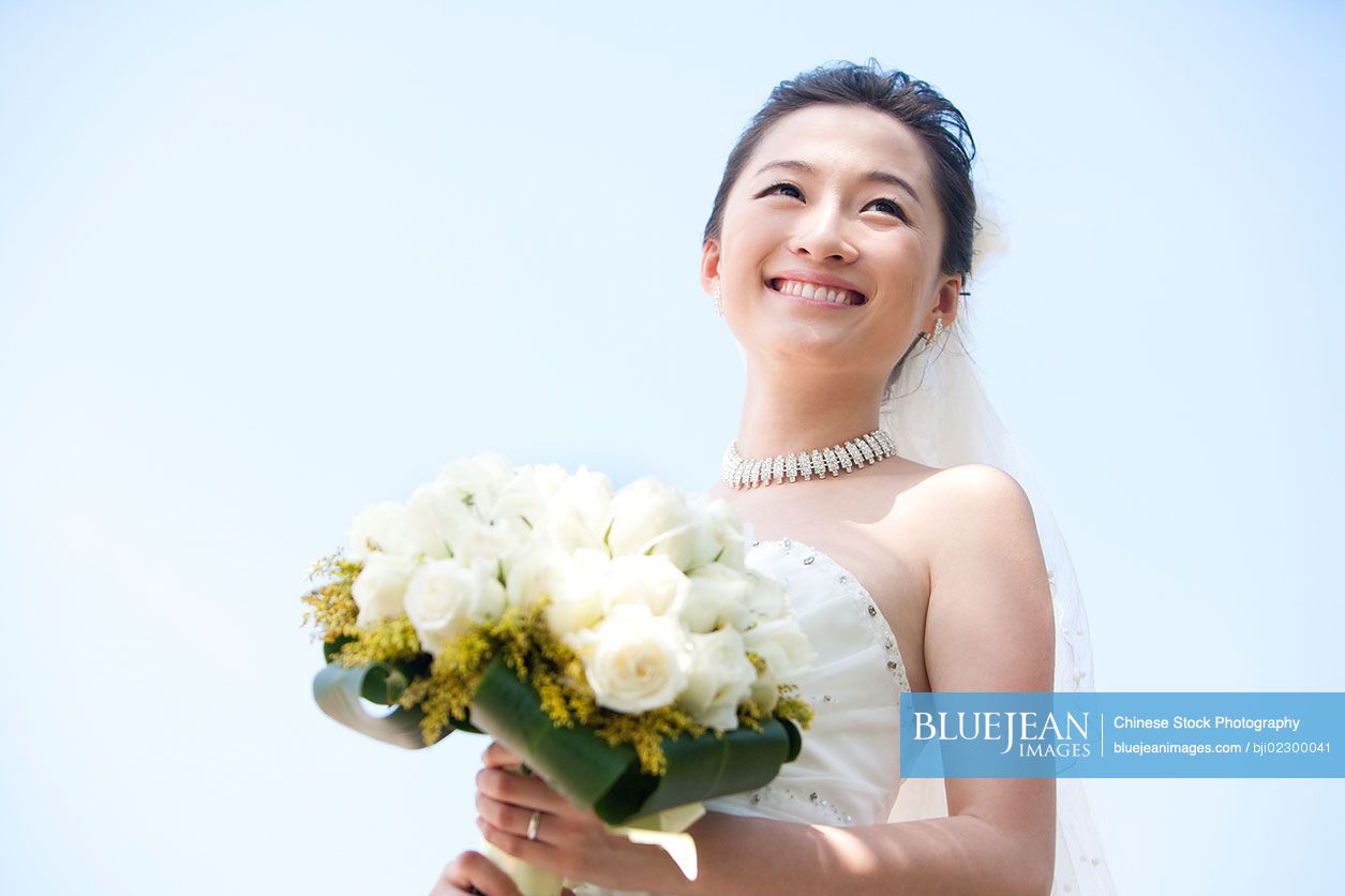 Happy Chinese bride holding bouquet