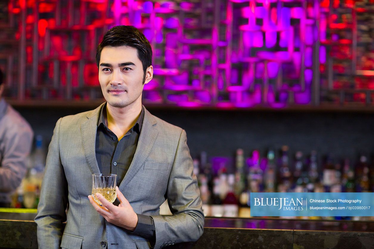 Young Chinese man having a drink at bar