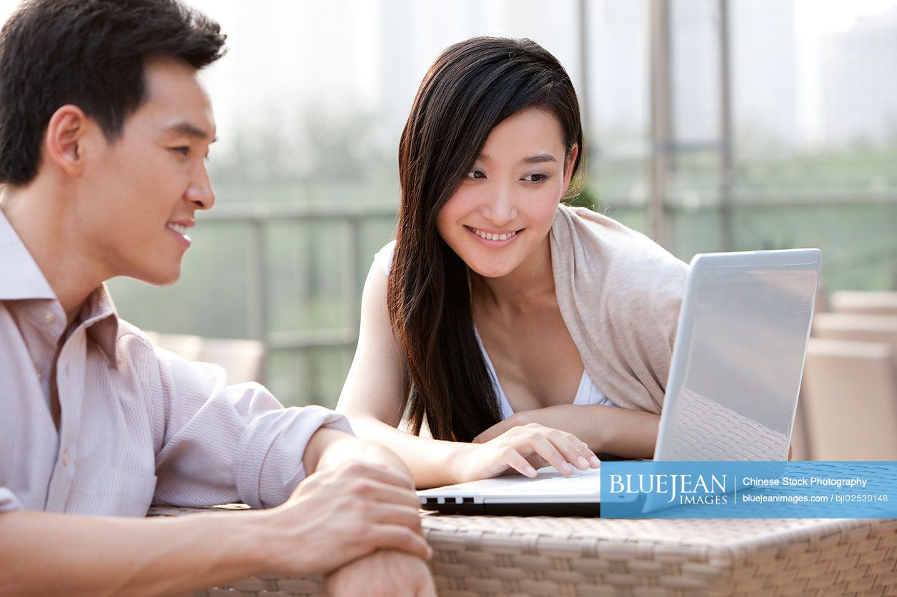 Chinese couple using laptop, outdoors