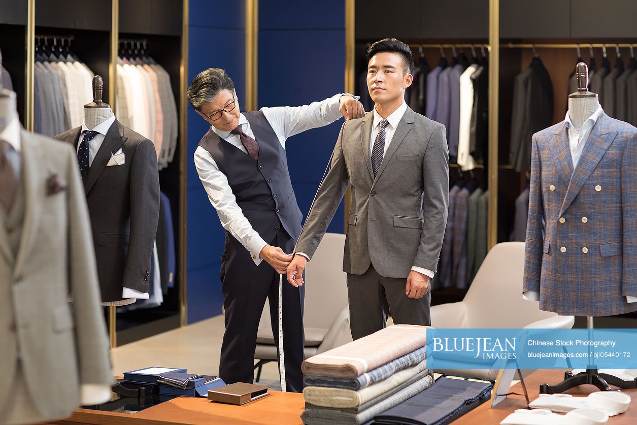 Chinese fashion designer taking measurement of customer