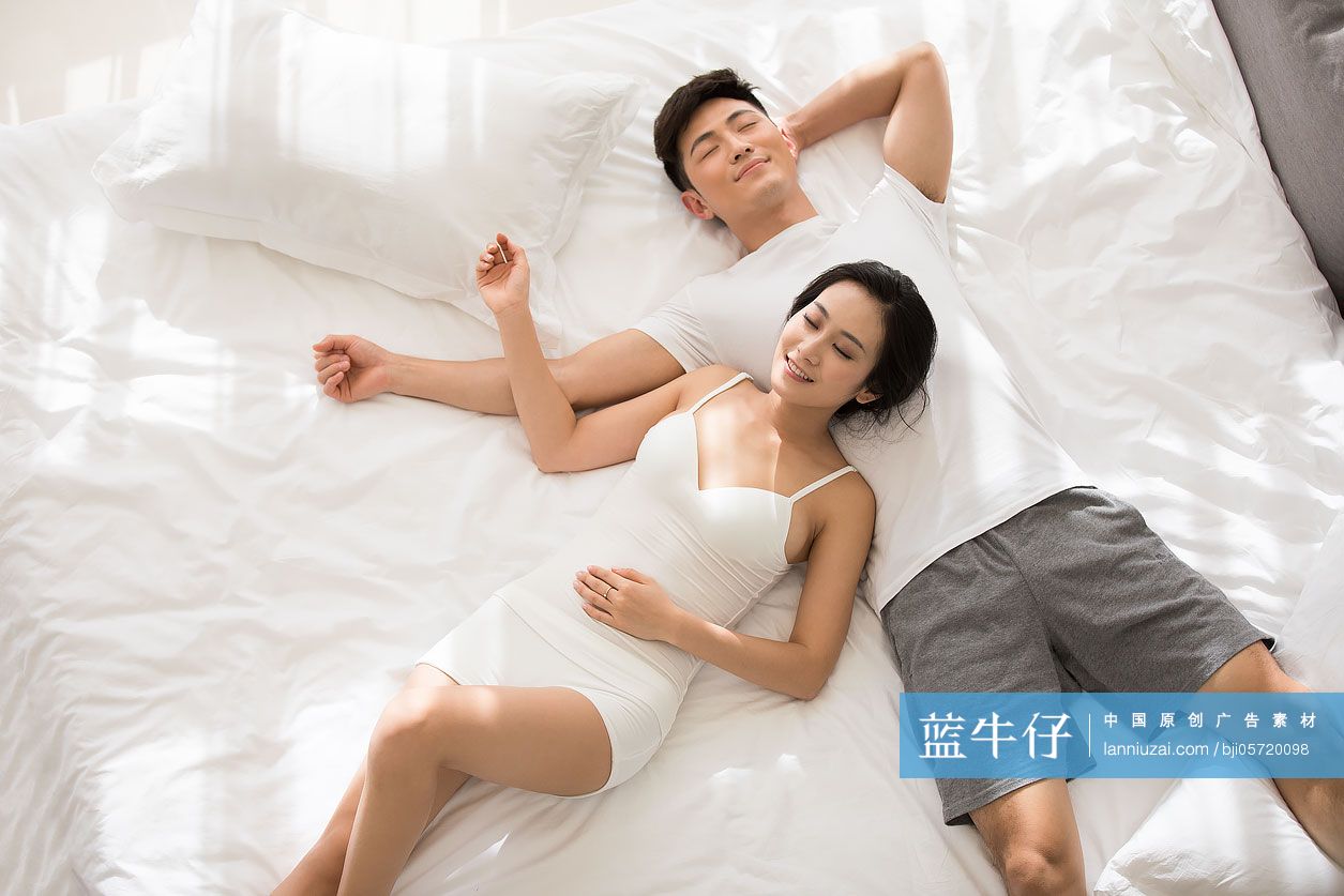 快乐的年轻情侣躺在床上睡觉