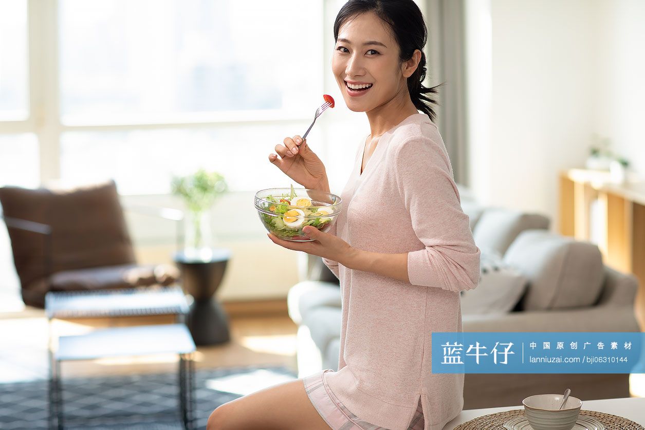 快乐年轻女士在家吃沙拉