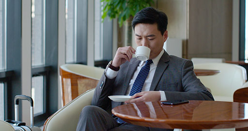Confident Chinese businessman drinking coffee in airport lounge,4K