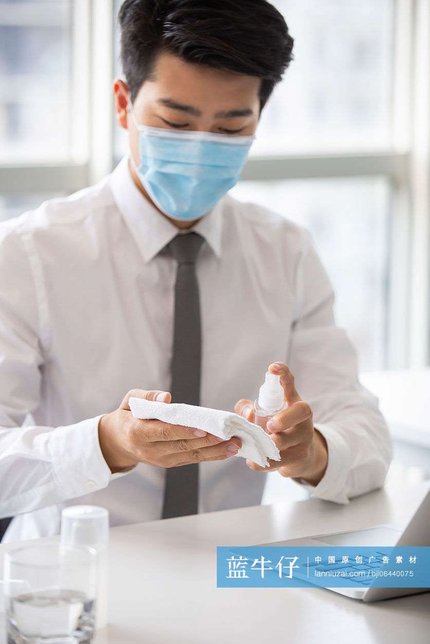 年轻的商务男士在办公室使用消毒液杀菌消毒