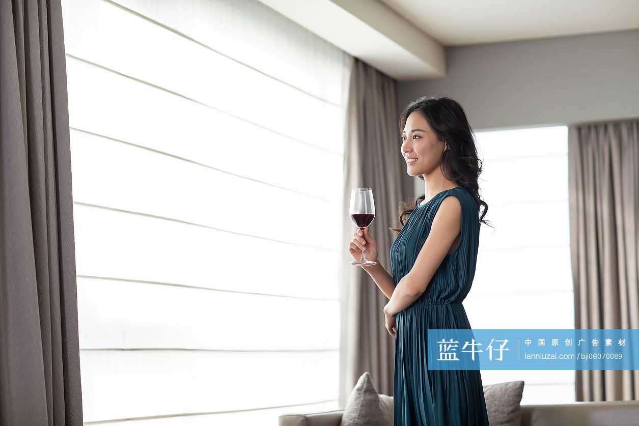 快乐的年轻女士在客厅喝红酒