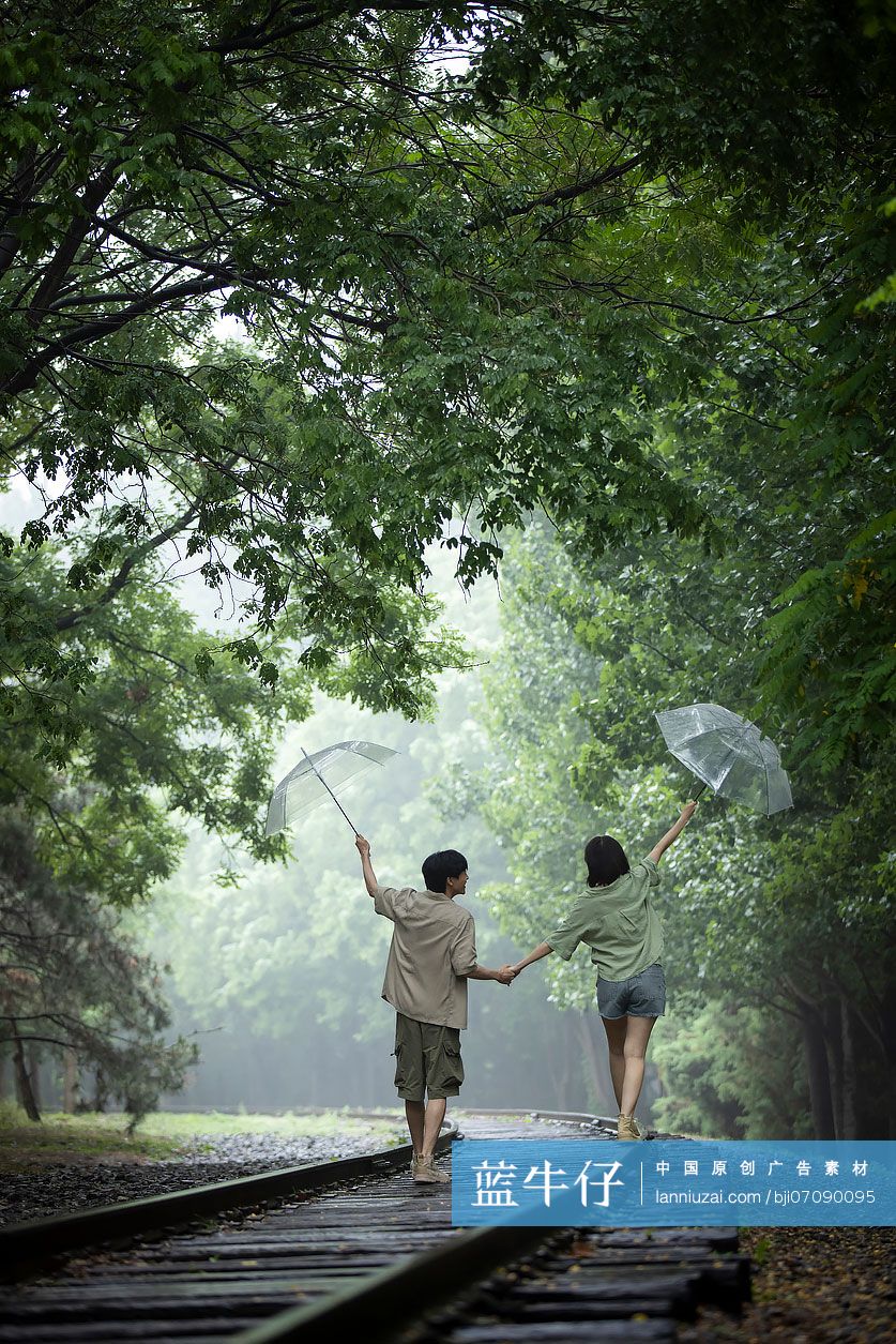 年轻情侣打着伞雨中散步