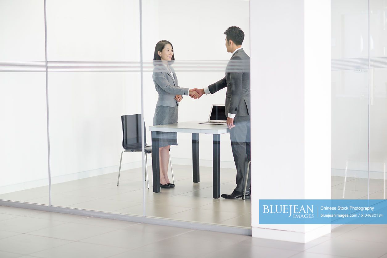 Chinese business person shaking hands in meeting room