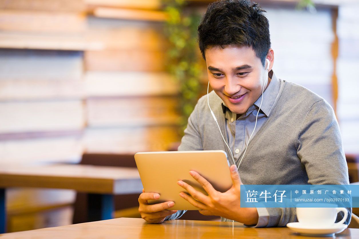 年轻男子在咖啡馆使用平板电脑观看视频