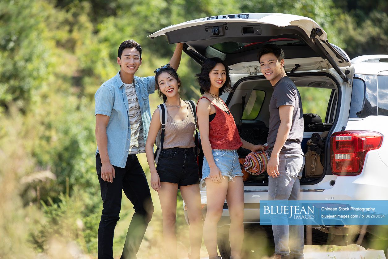 Happy young Chinese friends camping outdoors