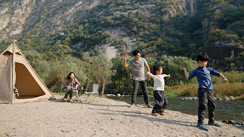 Happy young Chinese family camping outdoors