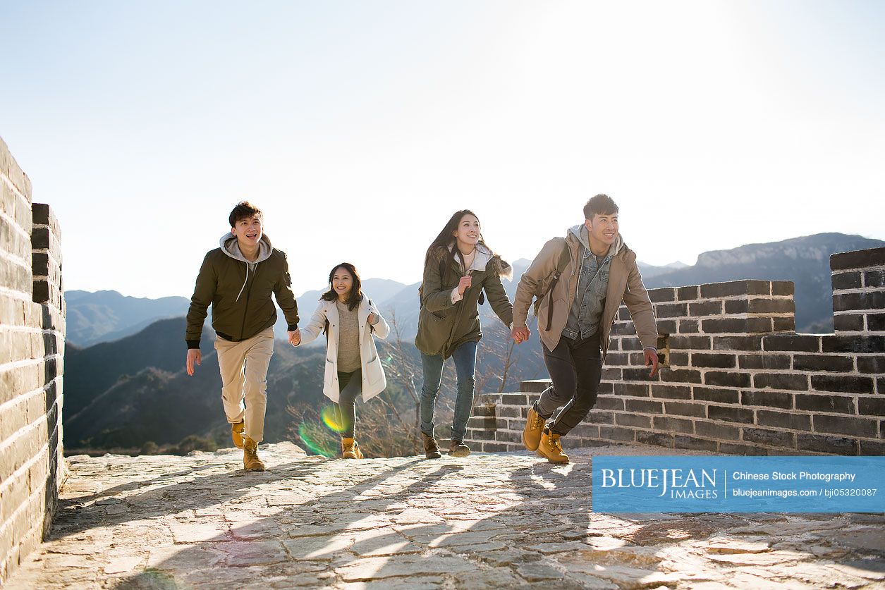 Happy young Chinese friends enjoying winter outing on the Great Wall