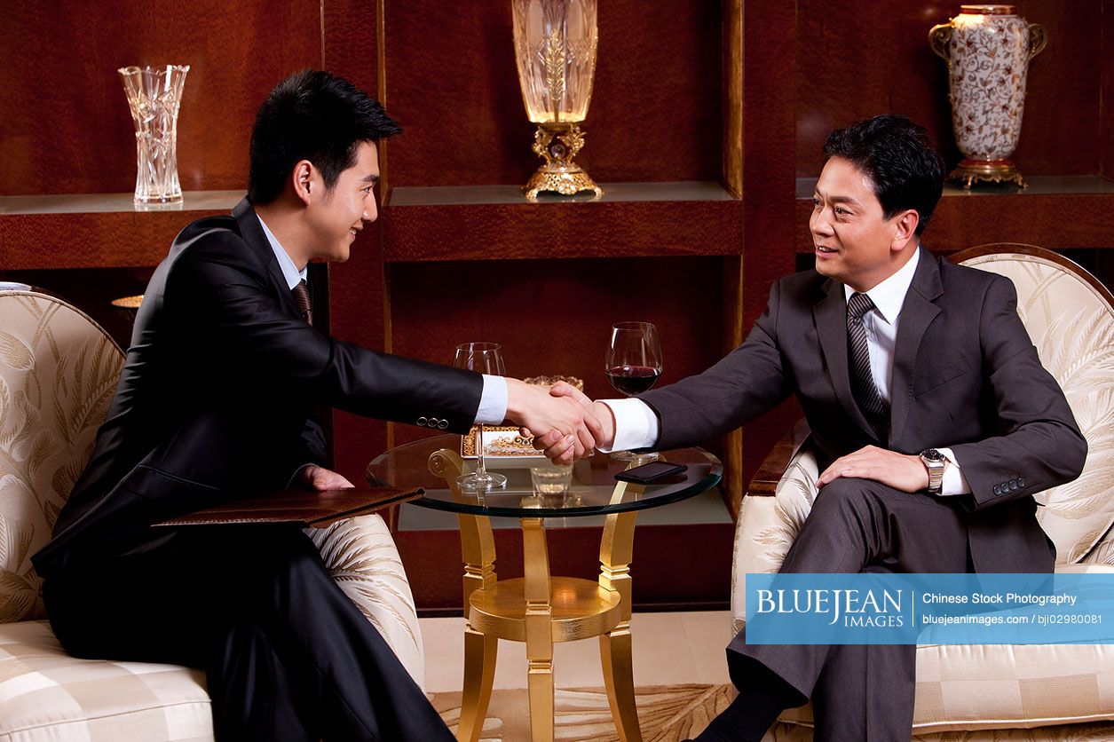 Chinese businessmen shaking hands in a luxurious room