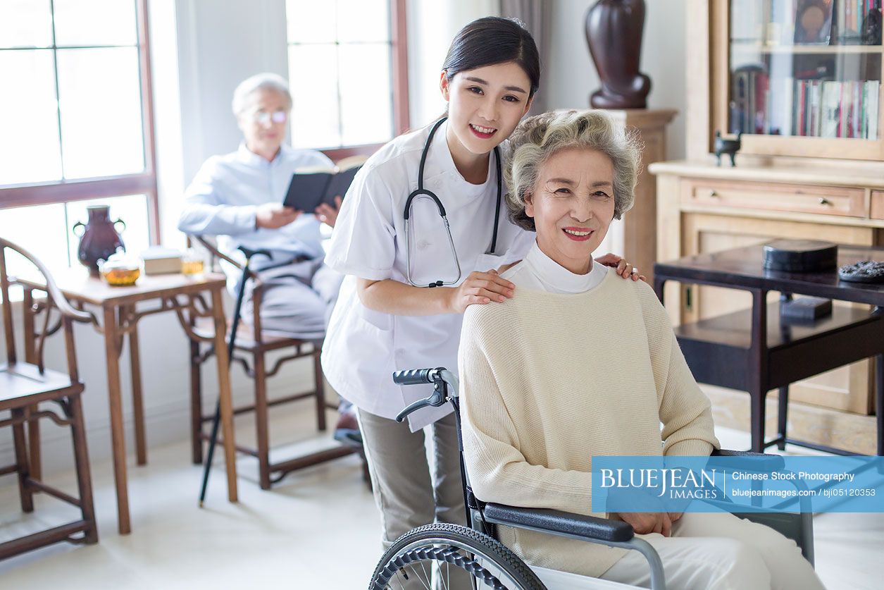 Chinese nursing assistant taking care of senior woman in wheel chair ...