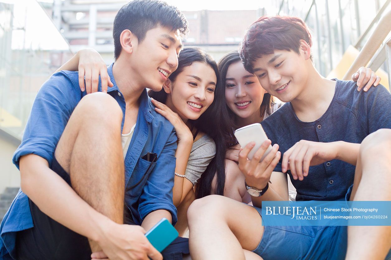 Young Chinese friends looking at a smart phone