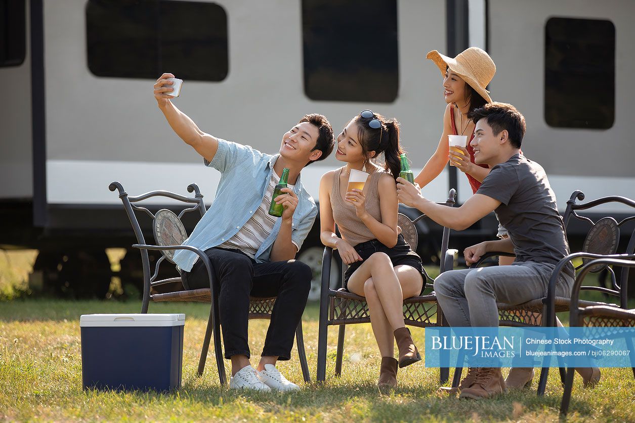 Happy young Chinese friends taking selfie outdoors