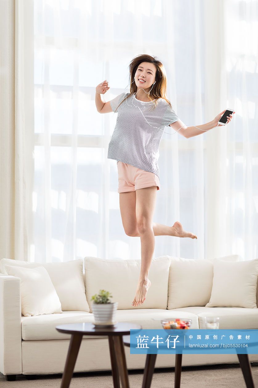 年轻女子在沙发上听音乐蹦跳
