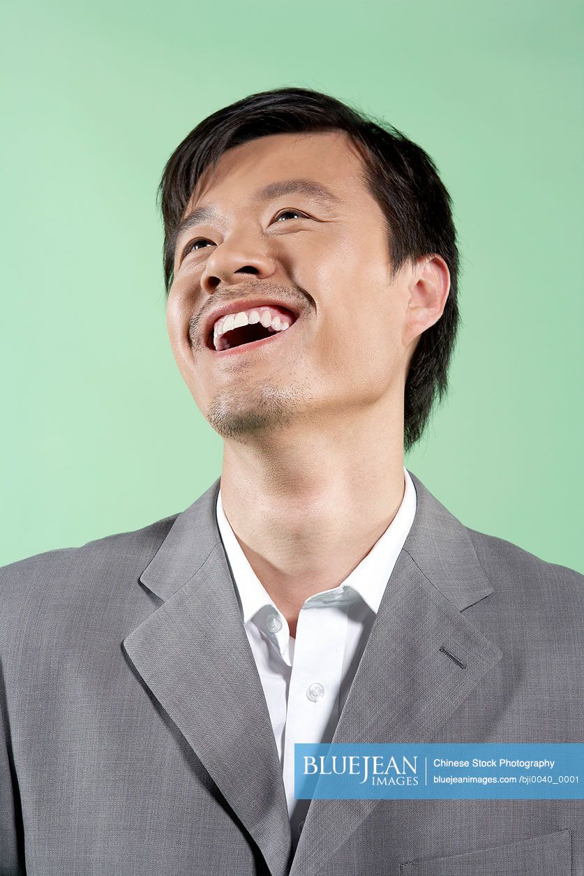 Young Chinese man looking up and laughing