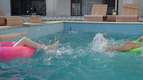 Happy family swimming and playing in the sparkling pool