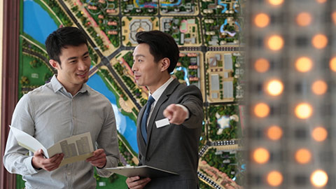 Young Chinese realtor showing architectural model to customer,HD