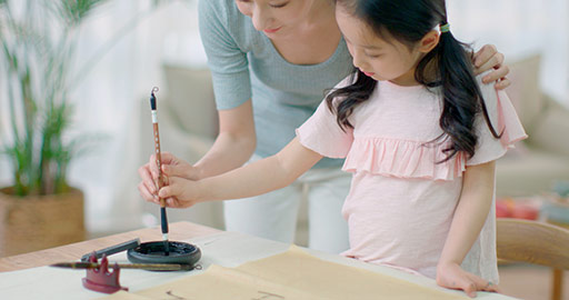 Happy Chinese mother and daughter writing calligraphy at home,4K