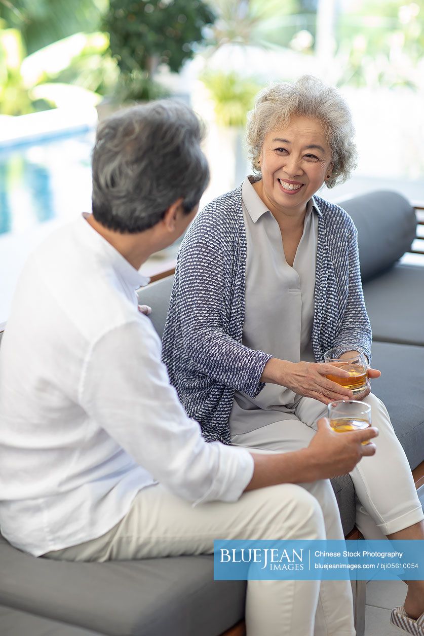 Happy senior Chinese couple relaxing on sofa