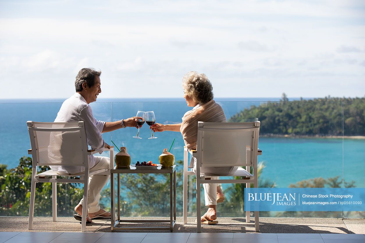 Happy senior Chinese couple relaxing on balcony