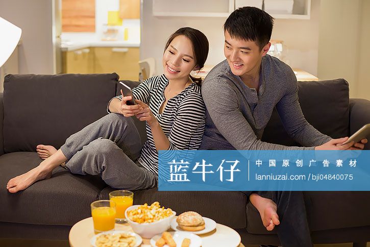 年轻情侣在客厅沙发上使用手机