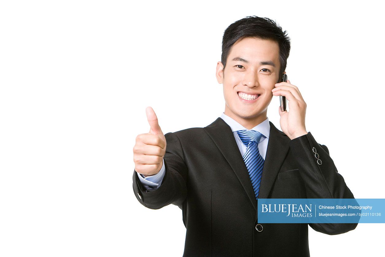 Cheerful Chinese businessman using mobile phone