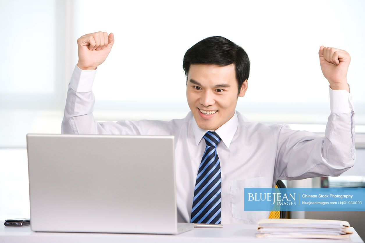 Happy Chinese office worker at his desk