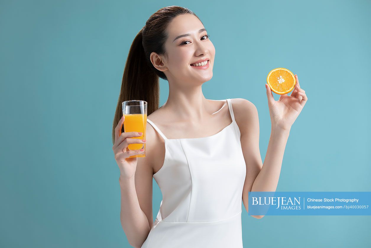 Beautiful young Chinese woman drinking orange juice