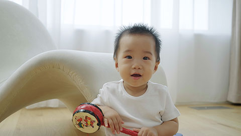 Baby playing with a rattle on the floor and then starts crawling