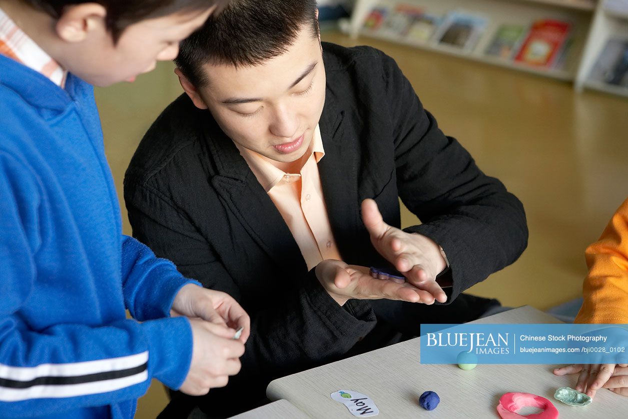 Teacher explaining to boy how to use play dough
