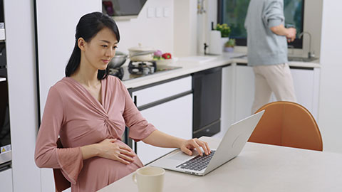 Young pregnant Chinese couple shopping on internet