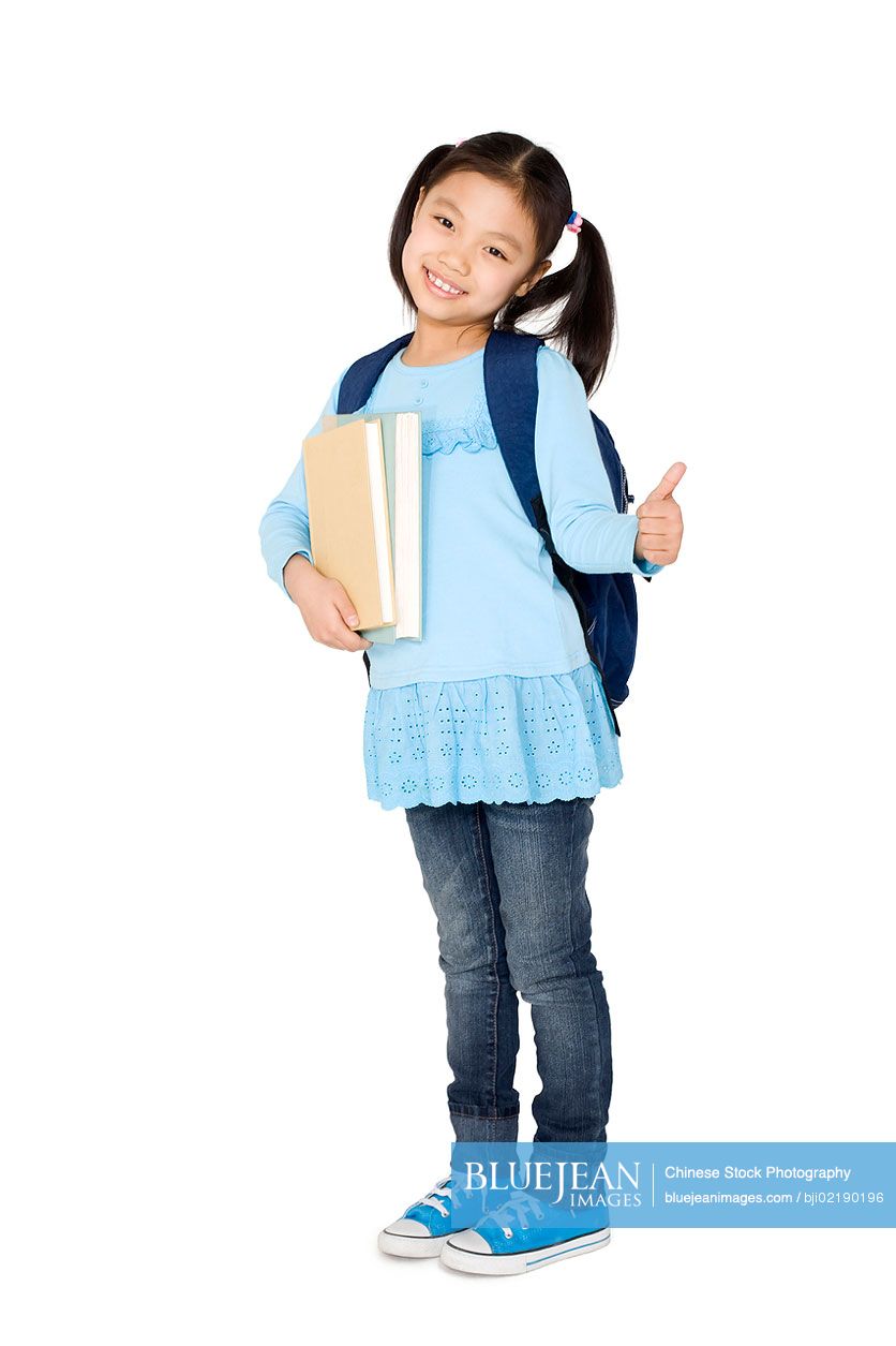 A young Chinese girl holding books and giving a thumbs up