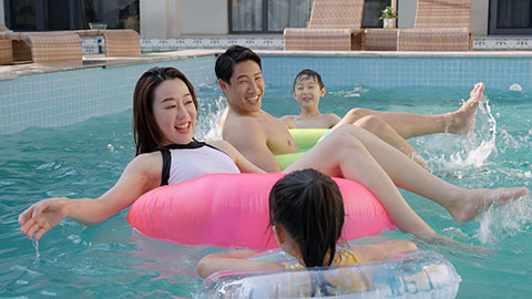 Happy family swimming and playing in the sparkling pool