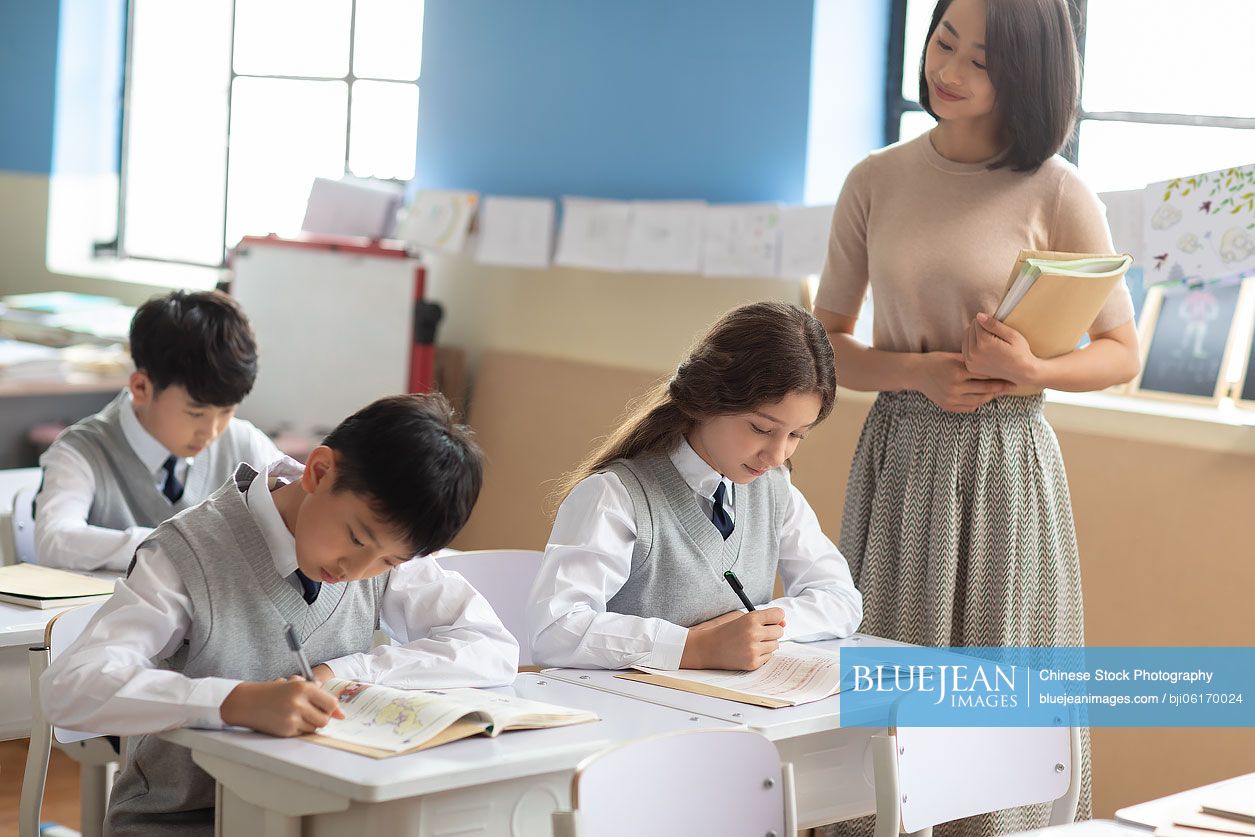Young Chinese teacher helping students in classroom-High-res stock ...