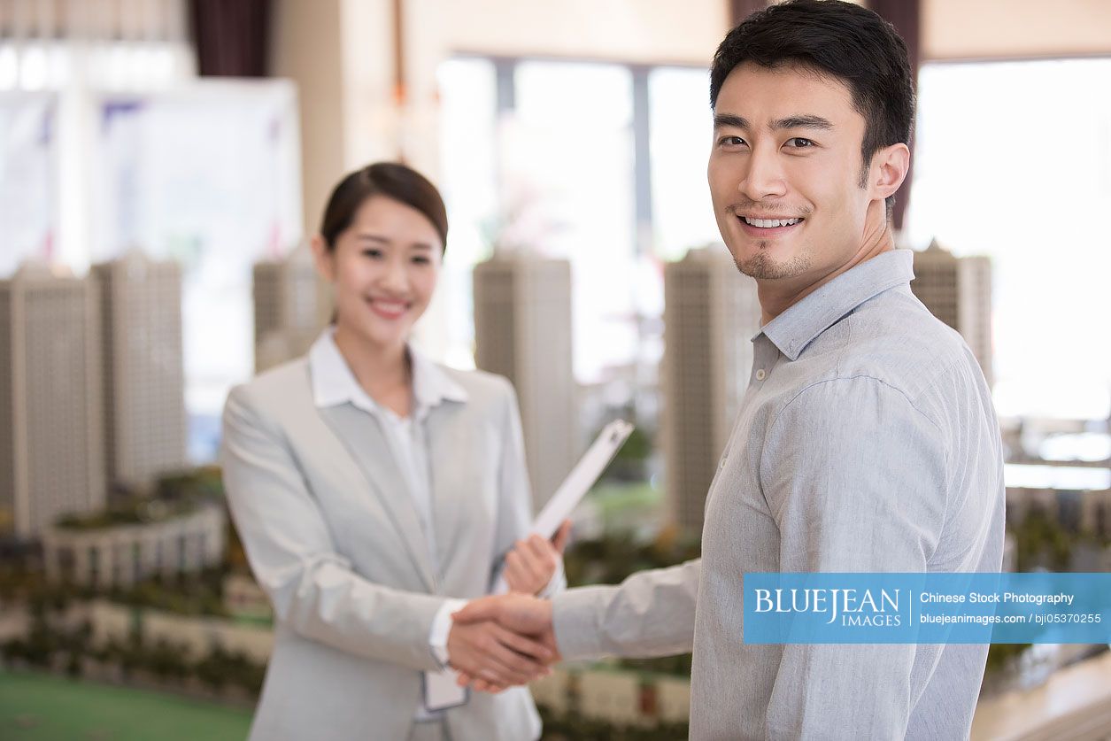 Happy young Chinese man shaking hands with realtor