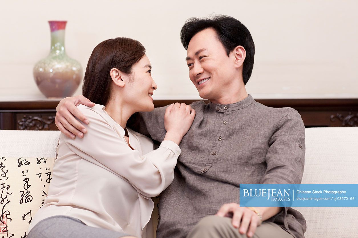 Loving Chinese couple sitting in sofa