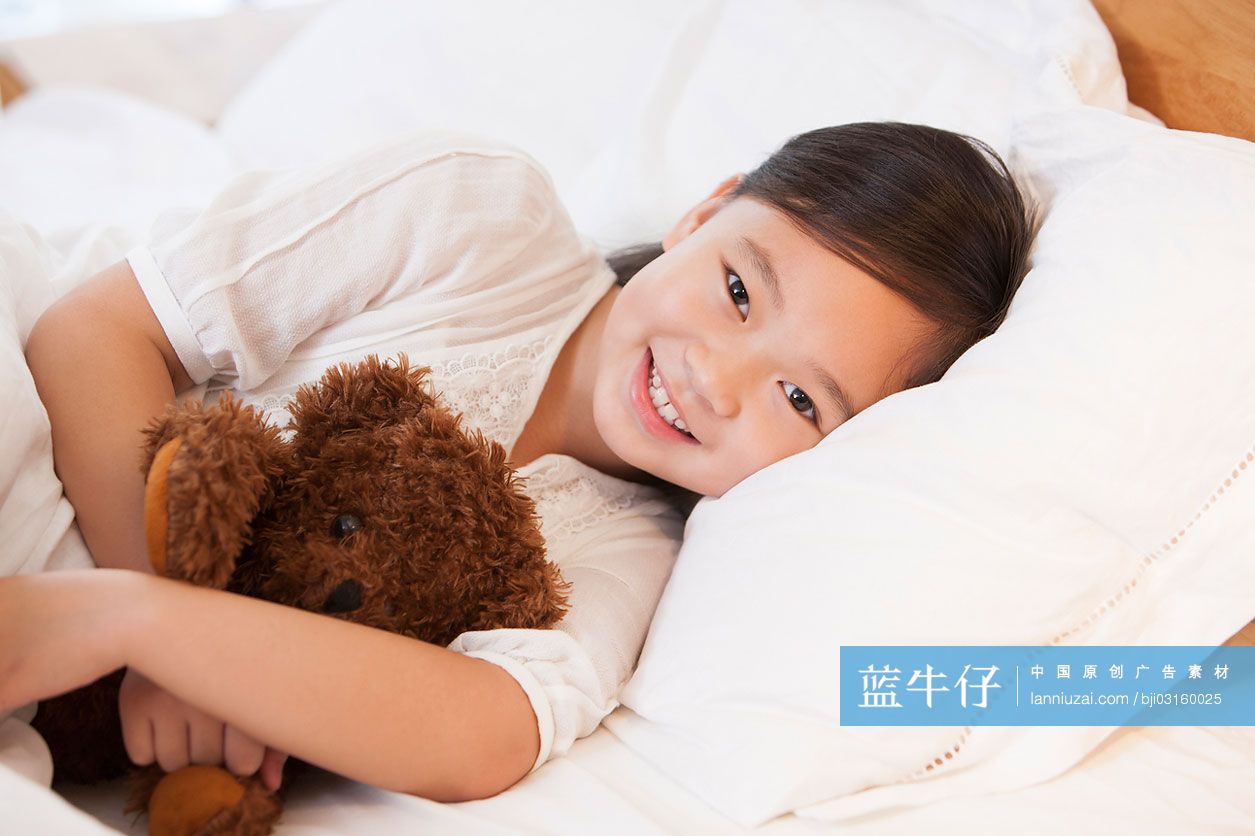 可爱的小女孩抱着泰迪熊在床上照片摄影图片_ID:121767755-Veer图库