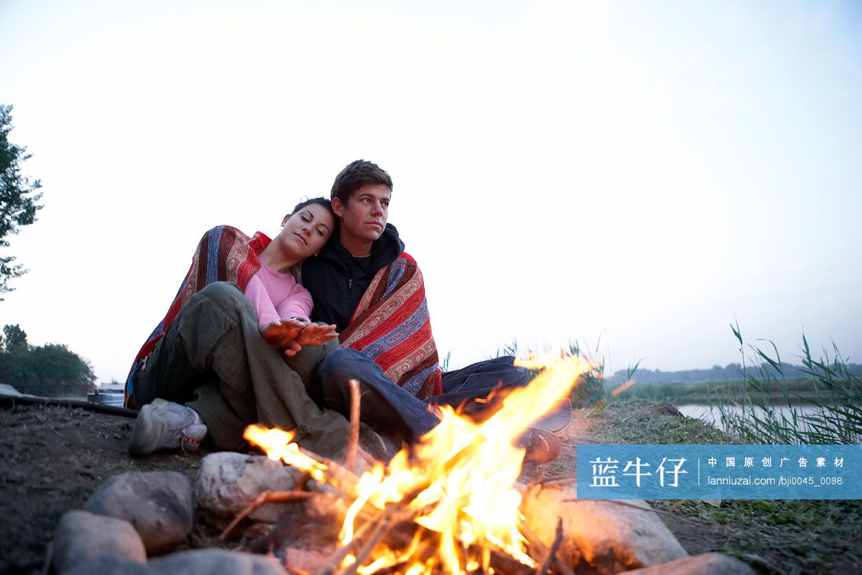 年轻情侣坐在篝火旁